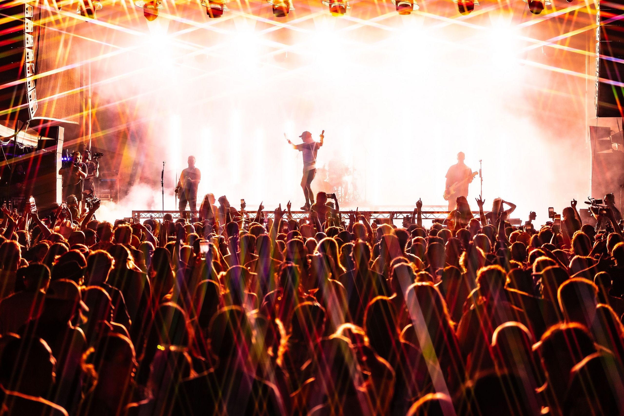 A vibrant concert scene with a band performing on stage, colorful lights, and a cheering crowd raising their hands in excitement.