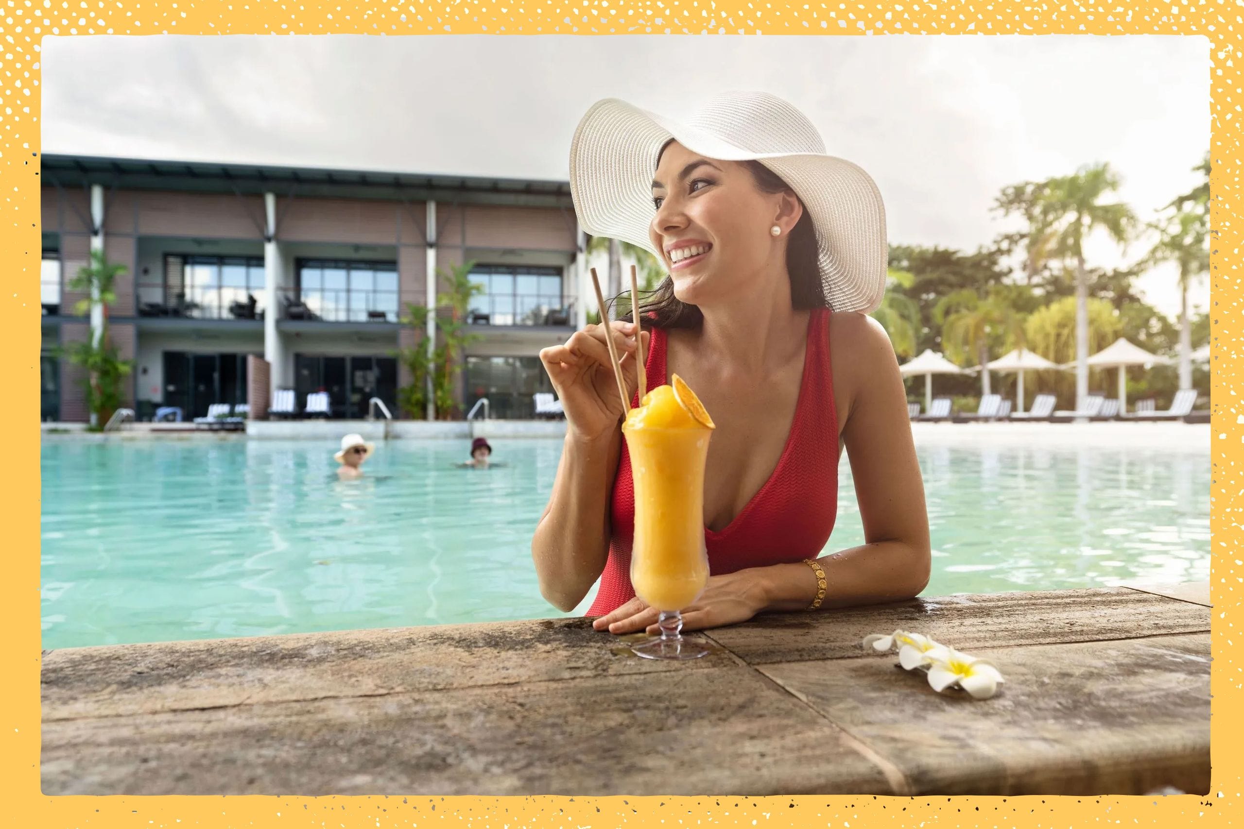 Woman in a red swimsuit and white hat enjoying a tropical drink at a poolside, with a resort building and palm trees in the background.