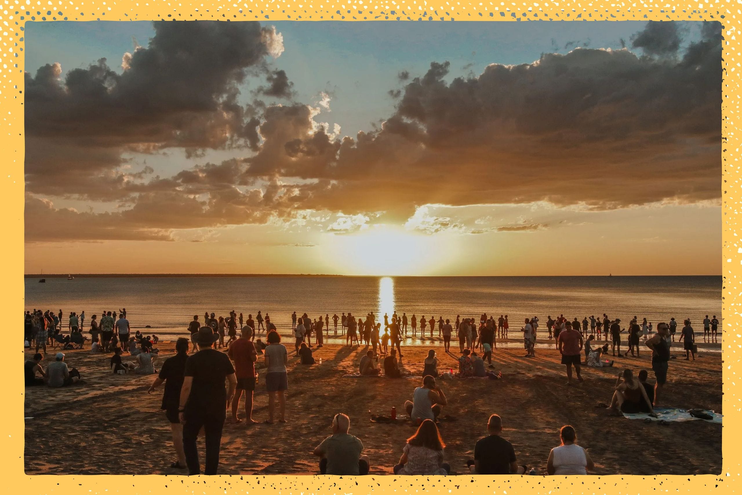 Crowd gathered on a beach at sunset, with the sun setting over the ocean and clouds in the sky, framed by a decorative border.